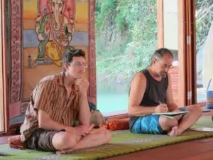 Randy and Ross seated on Thai mats attending a Thai massage class in Thailand